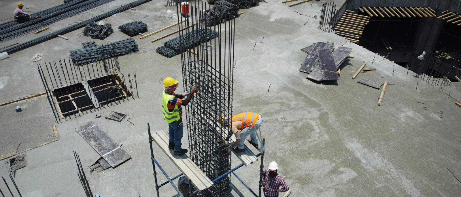 Construction workers tying rebar on a concrete deck