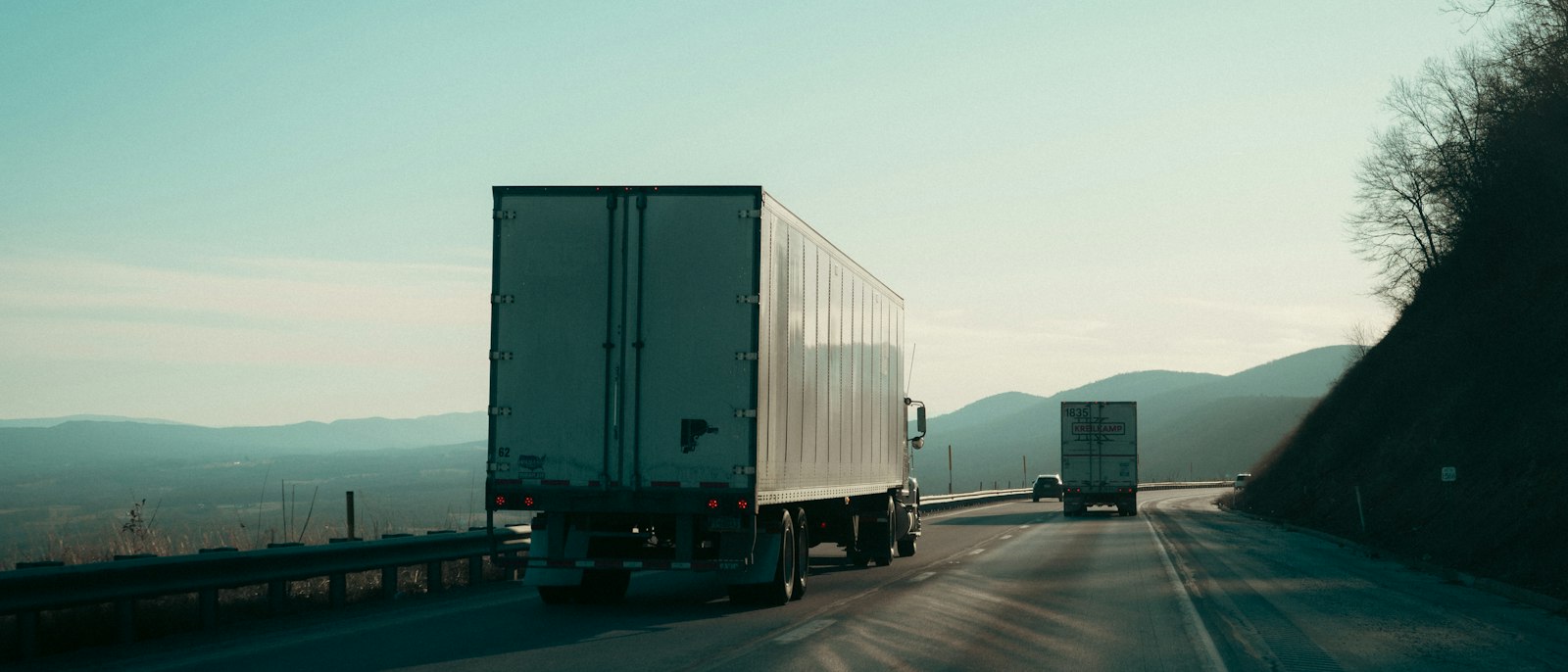 Two semi-trucks driving on a highway
